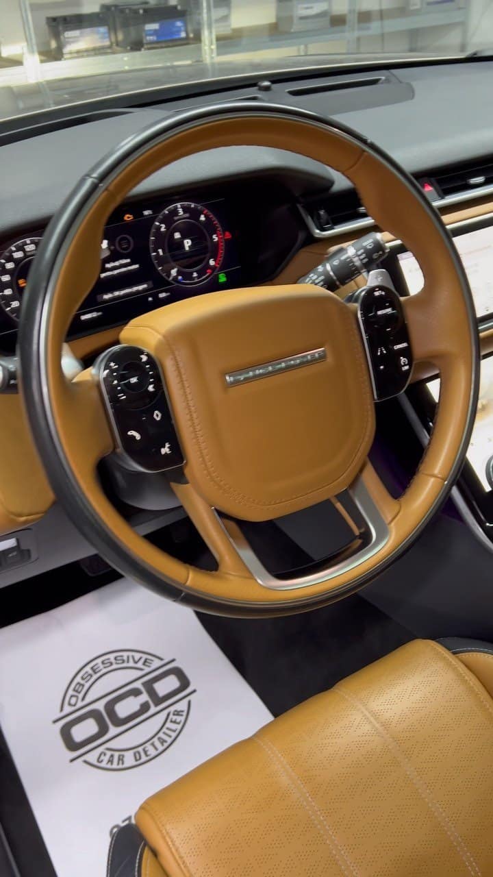 Interior de Range Rover cu volan maro, după curățare, cu covorașul de hârtie cu ștampila OCD pe podea.