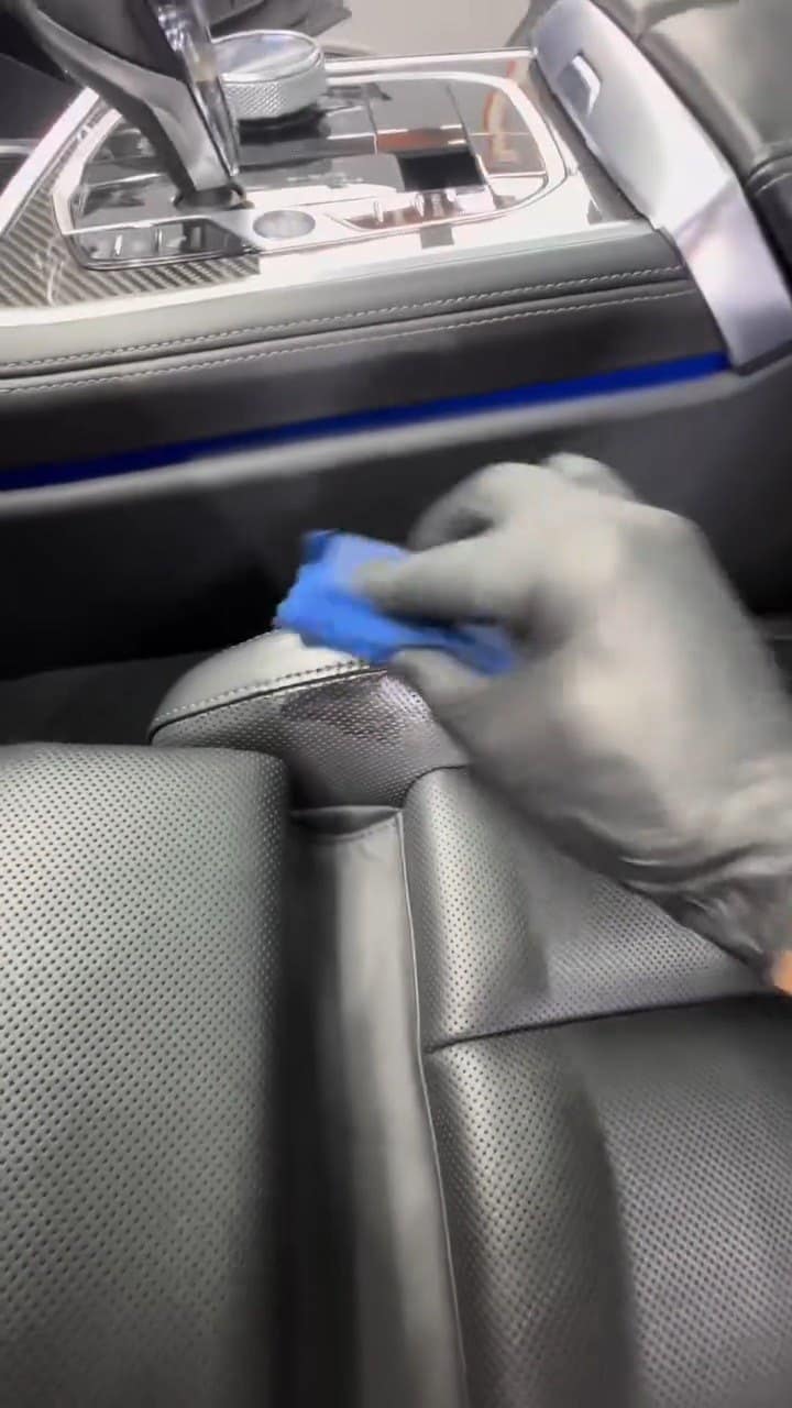 Aplicarea tratamentului ceramic pe pielea unui BMW Seria 8, cu mănuși și aplicator.