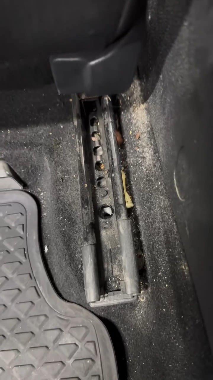Șina unui scaun de VW Golf, plină de nisip și mizerie, cu scaunul scos.